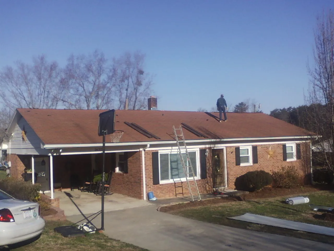Roofer stripping a shingle roof on a brick ranch before metal panels in Rockwell