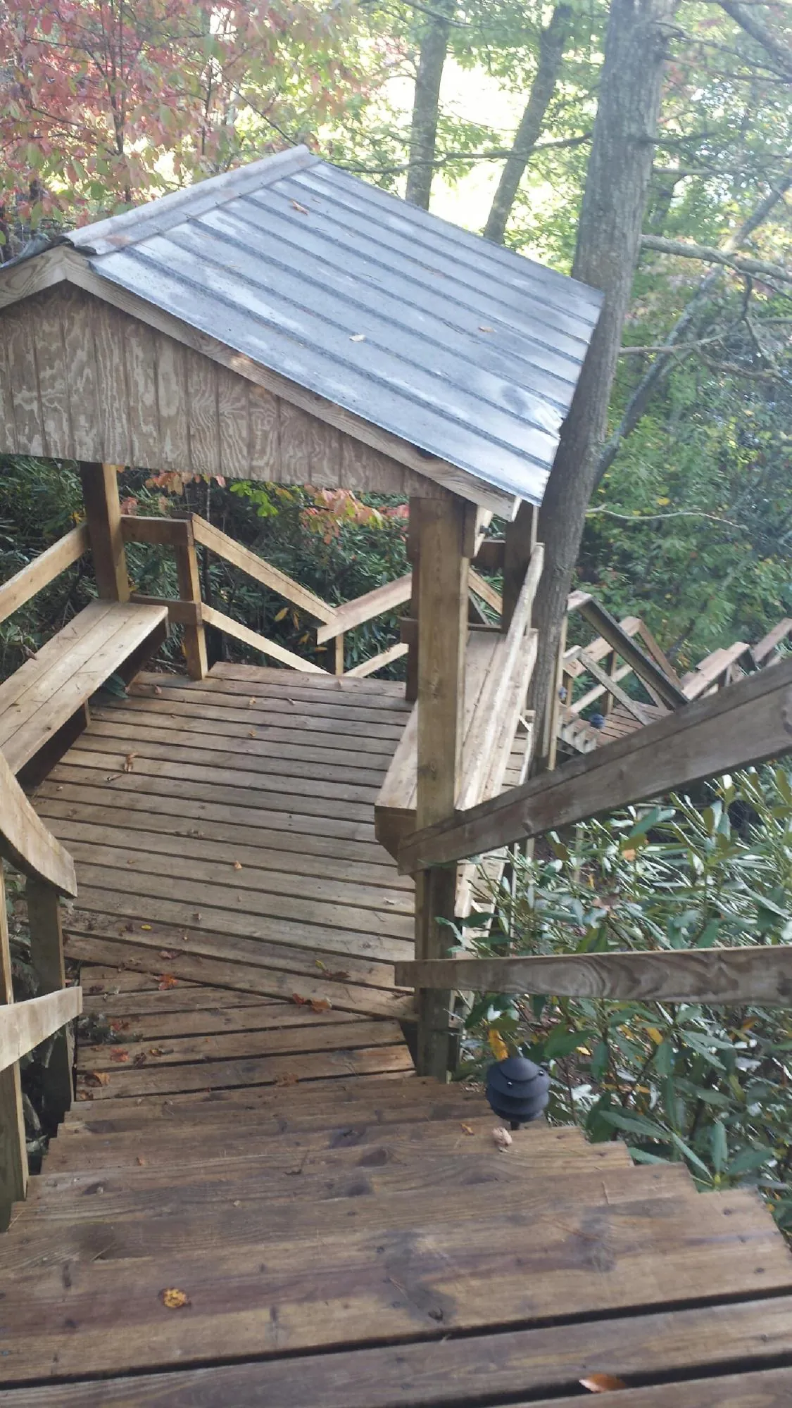 Metal roofed shelter over wooden steps on a wooded walkway — Skylight Repair & Installation work by our crew in Rockwell